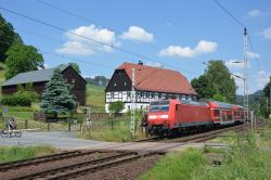 Bombardier Traxx E-Lok der DB-Baureihe 146 als S1 der S-Bahn Dresden im Elbtal am Bahnübergang bei Kurort Rathen mit altem Bauernhof