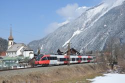 Eletrotriebwagen Bombardier Talent Reihe 4024 der ÖBB Österreich als S5 der S-Bahn Tirol von Scharnitz nach Innsbruck im Winter bei Schnee mit Kirche und Alpen